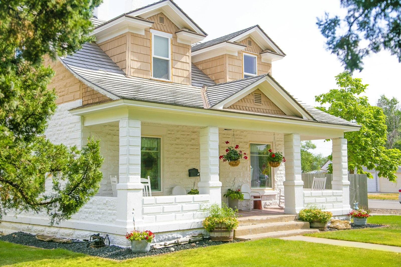 Craftsman bungalow with a white front porch and hanging flower baskets