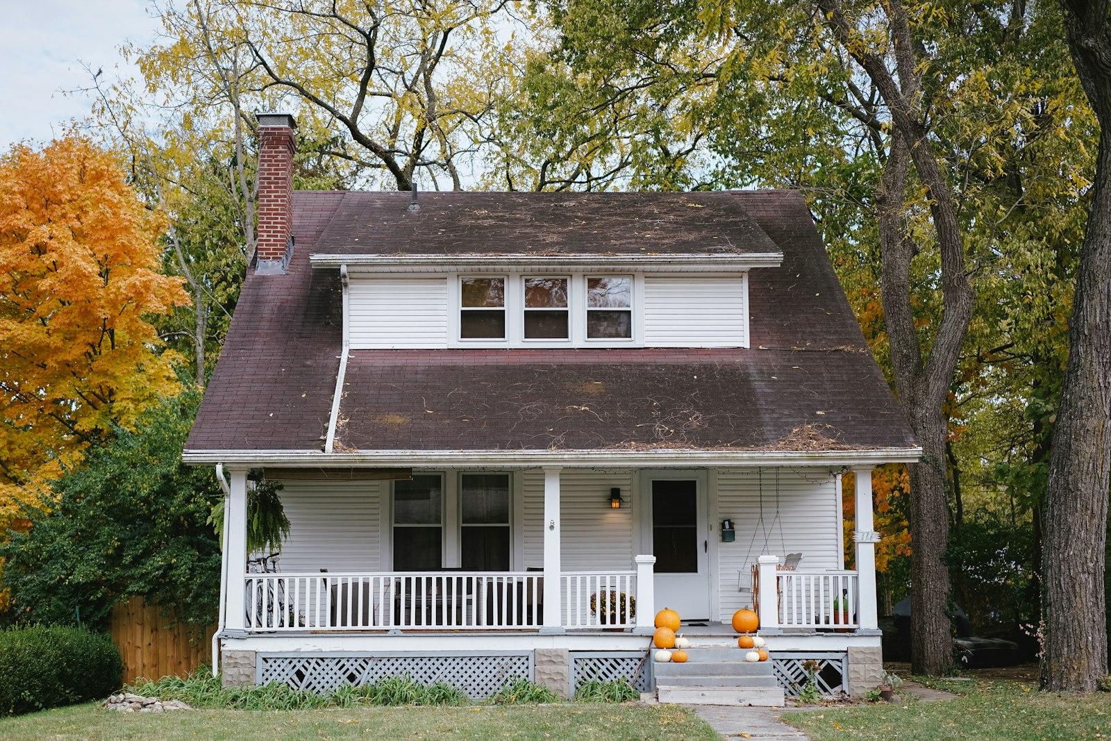 Craftsman home under autumn maples with a wood fence